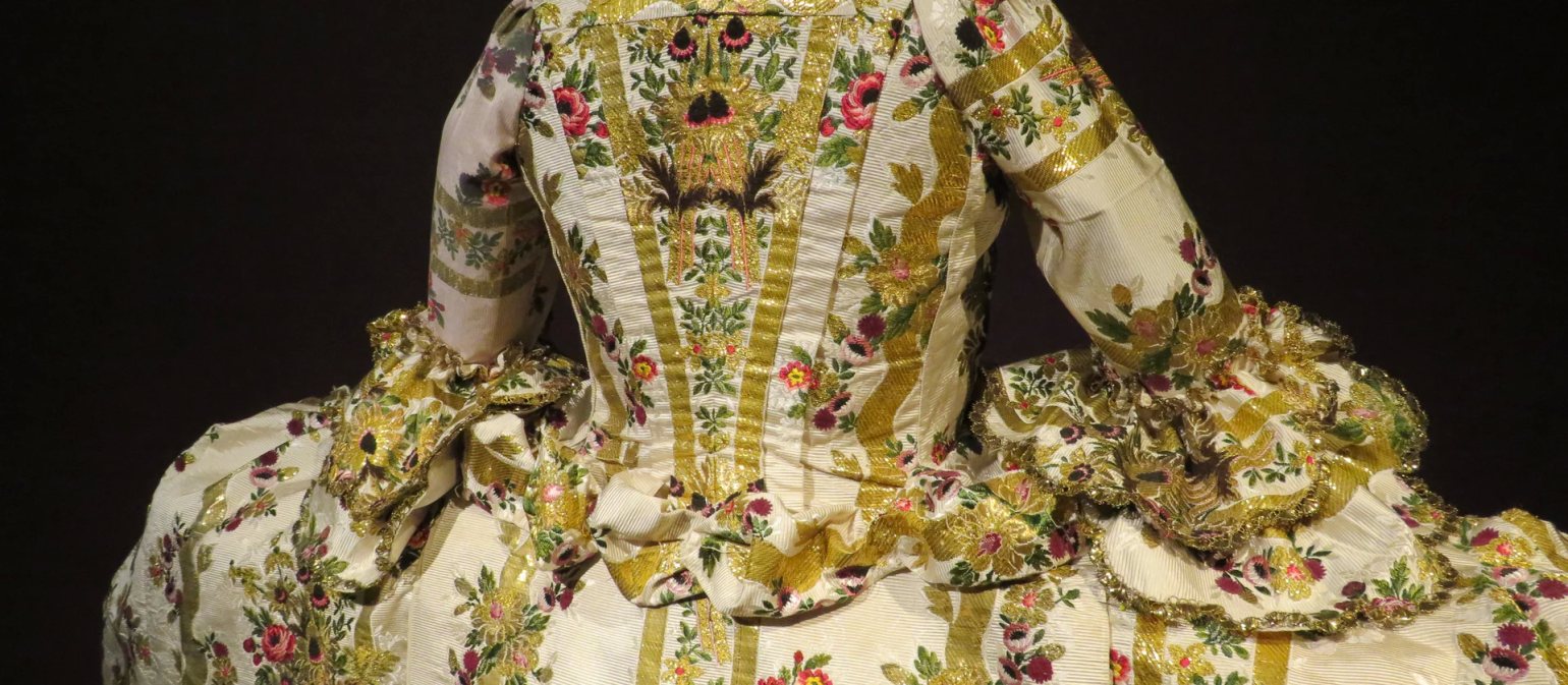 The back of a floral and gold detailed dress, part of ‘A Dress Fit for a King’ exhibition at Berrington Hall, Herefordshire, UK.