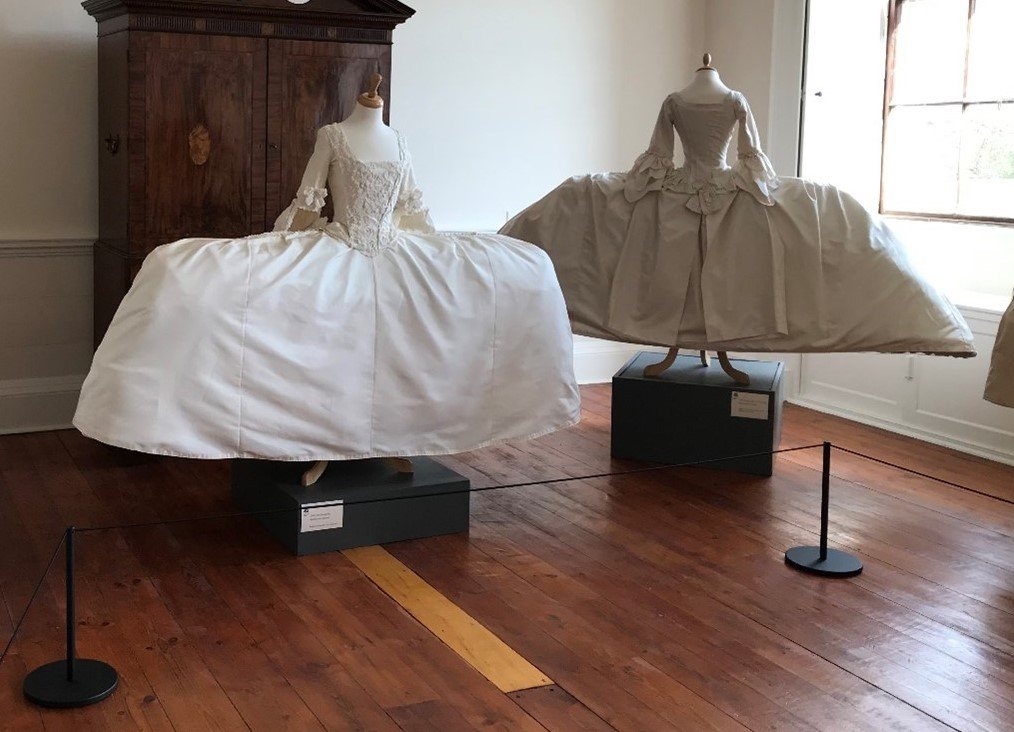 Two cream Mantua dresses in the ‘A Dress Fit for a King’ exhibition at Berrington Hall, protected by black Absolute Freestanding Barriers and cord.