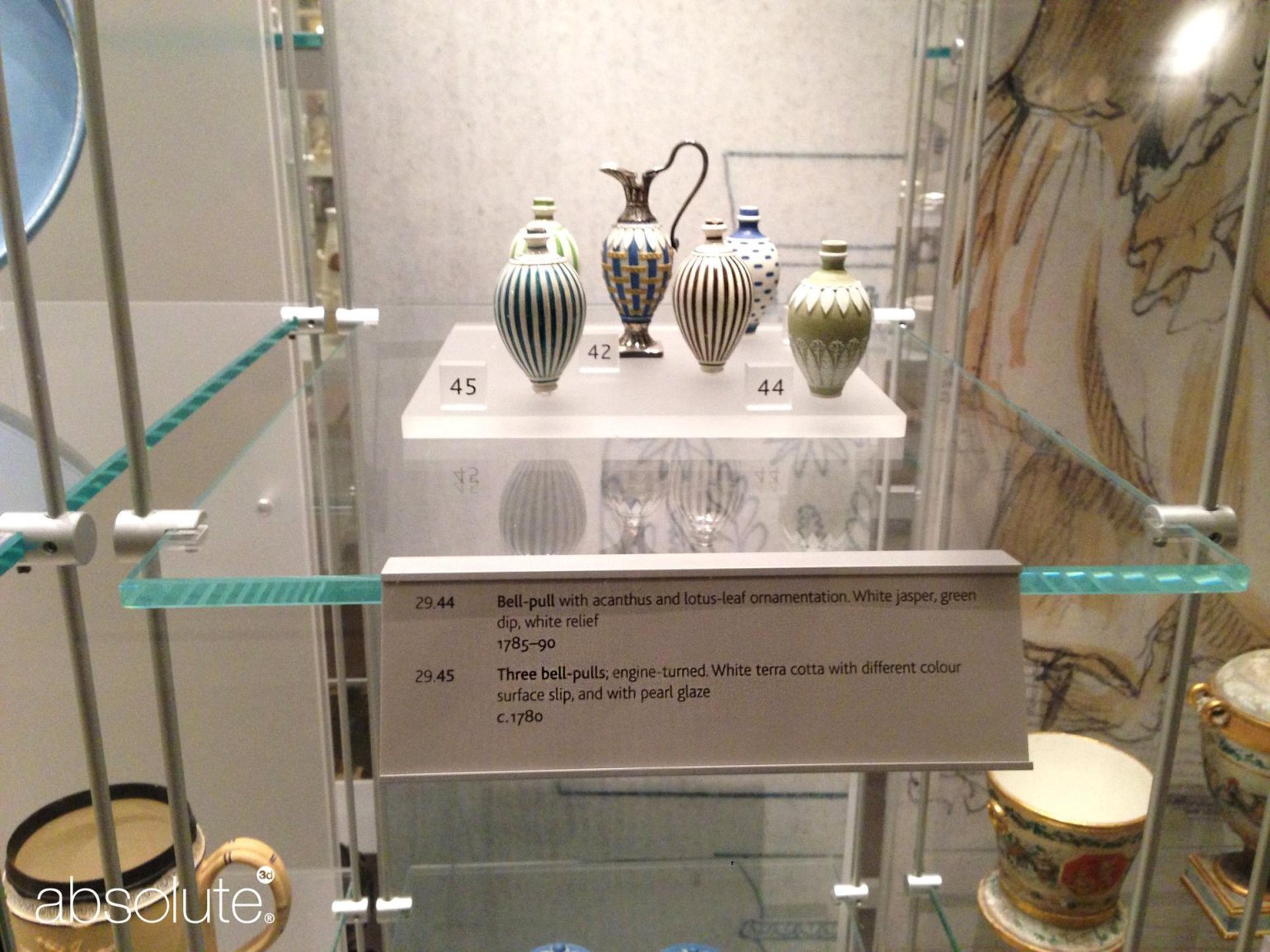 Ornements antiques dans le boîtier en verre et informations connexes affichées sur un support d'étiquette de bord d'étagère. Ornements antiques dans le boîtier en verre et informations connexes affichées sur un support d'étiquette de bord d'étagère.