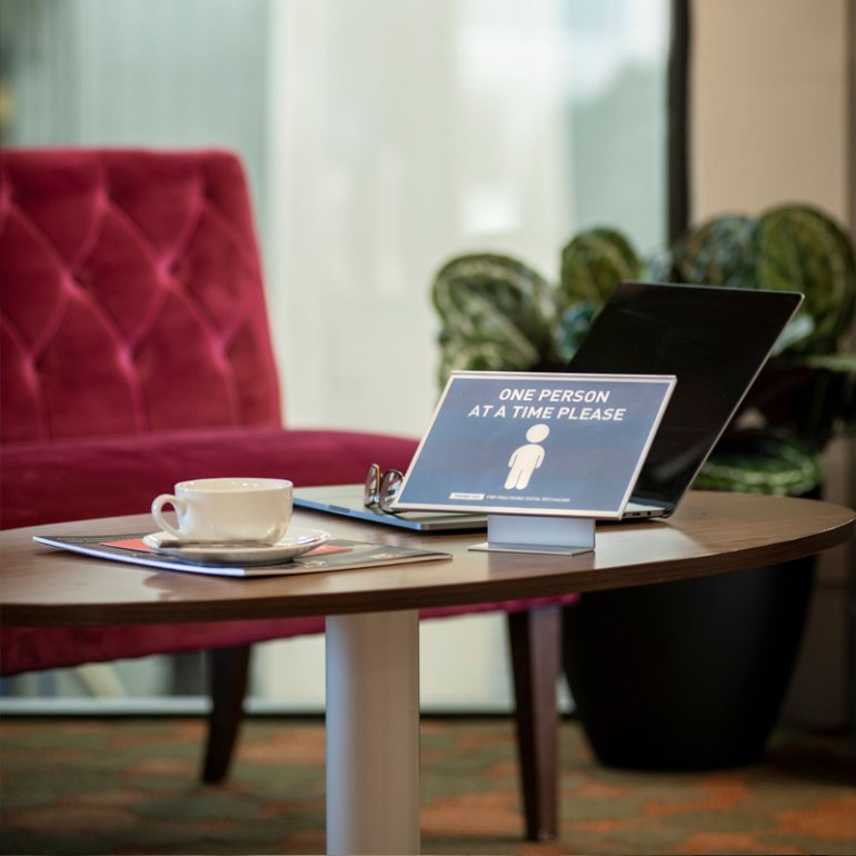 Le porte-étiquette autoportant absolu placé sur un tableau dans un environnement de bureau informant les mesures de distanciation sociales.