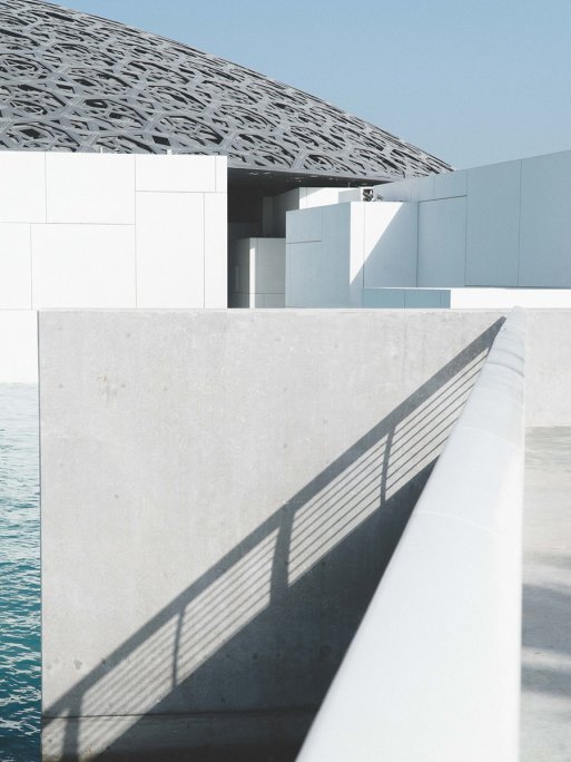 Plan extérieur du Louvre Abu Dhabi, mettant en valeur les différentes textures architecturales et le toit en forme de dôme argenté. Plan extérieur du Louvre Abu Dhabi, mettant en valeur les différentes textures architecturales et le toit en forme de dôme argenté.